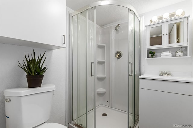 bathroom featuring vanity, toilet, a textured ceiling, and a shower with shower door