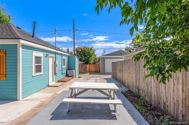 view of patio with an outdoor structure, central AC unit, and a garage