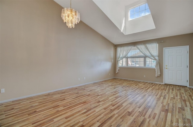 1343 Villa Grv, Monument, CO 80132 - unfurnished living room with plenty of natural light, a skylight, a chandelier, light wood-type flooring, and high vaulted ceiling