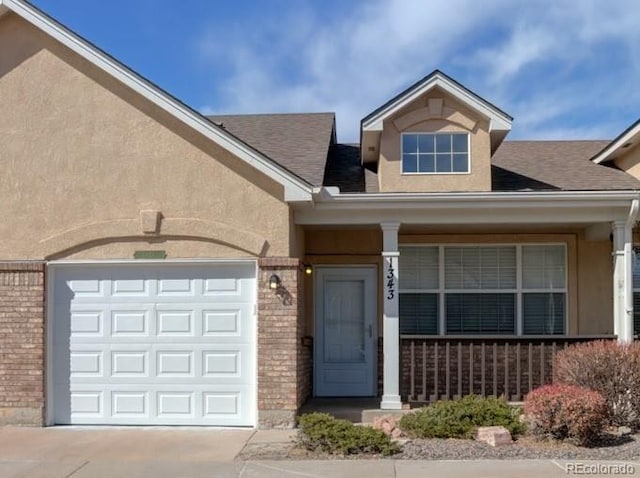 1343 Villa Grv, Monument, CO 80132 - view of front of house with concrete driveway, brick siding, covered porch, and roof with shingles