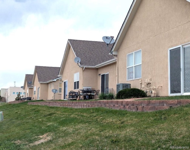 1343 Villa Grv, Monument, CO 80132 - rear view of property featuring stucco siding, a lawn, roof with shingles, and cooling unit