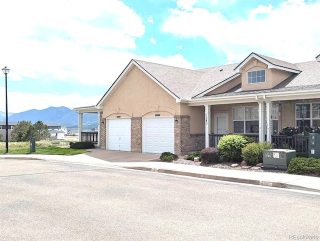 1343 Villa Grv, Monument, CO 80132 - view of property featuring concrete driveway, an attached garage, a mountain view, a shingled roof, and covered porch