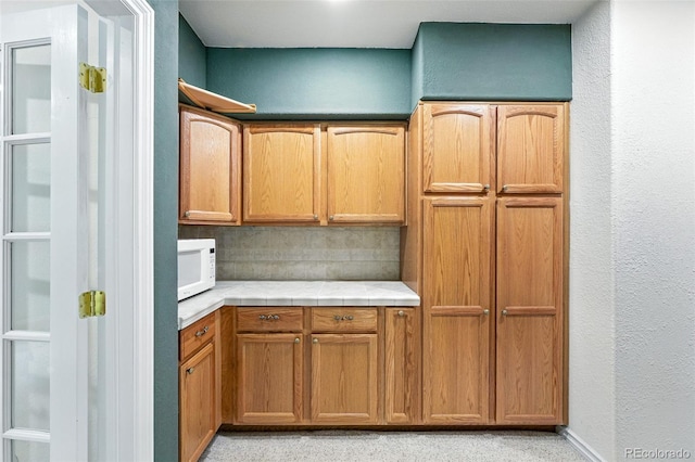5731 S Yampa St, Centennial, CO 80015 - kitchen with white microwave, tile countertops, a textured wall, and brown cabinets