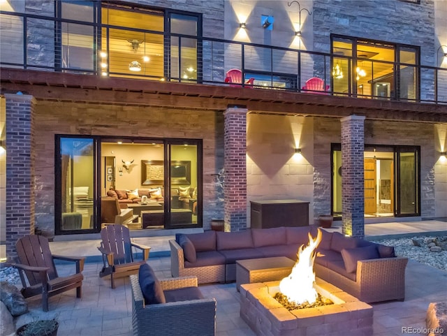 view of patio / terrace with a balcony and an outdoor living space with a fire pit