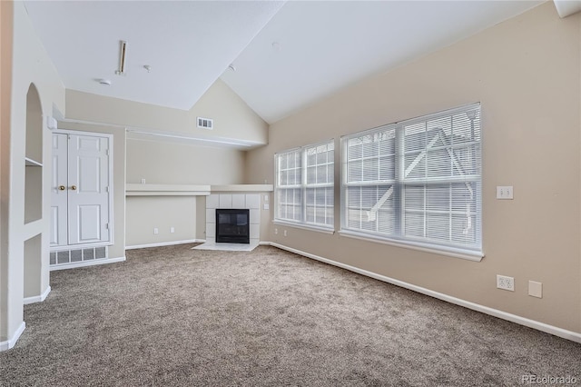 unfurnished living room featuring a tile fireplace, carpet, and vaulted ceiling