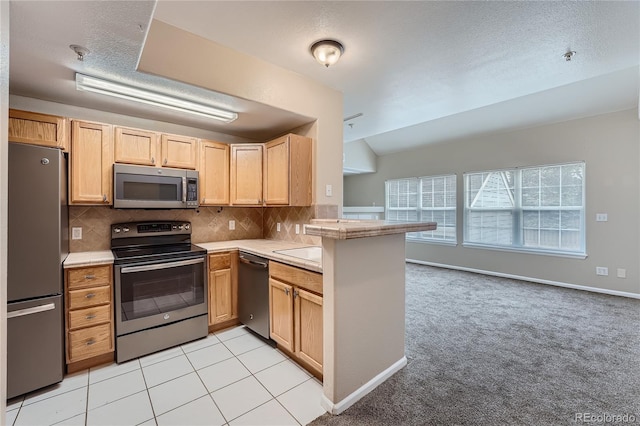 kitchen featuring lofted ceiling, backsplash, light tile patterned floors, a textured ceiling, and stainless steel appliances