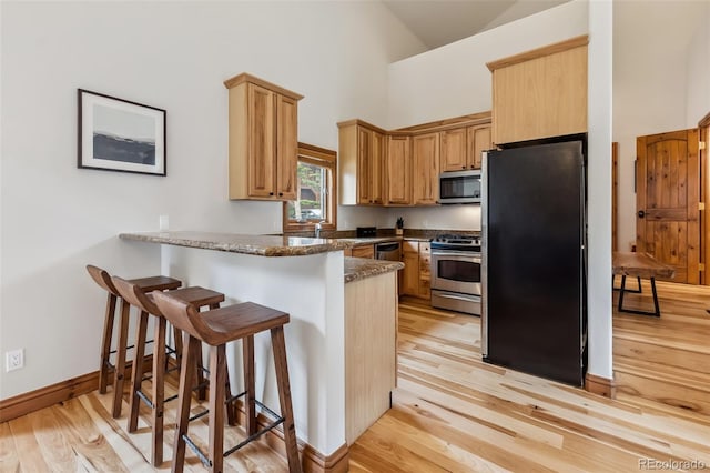 1152 Ski Hill Rd, Breckenridge, CO 80424 - kitchen with appliances with stainless steel finishes, a peninsula, high vaulted ceiling, light wood-type flooring, and a breakfast bar area