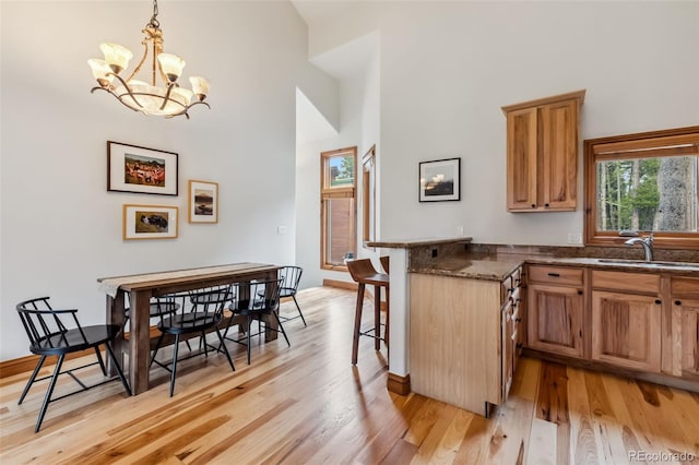 1152 Ski Hill Rd, Breckenridge, CO 80424 - kitchen featuring a breakfast bar area, light wood-style floors, a chandelier, a high ceiling, and dark stone counters