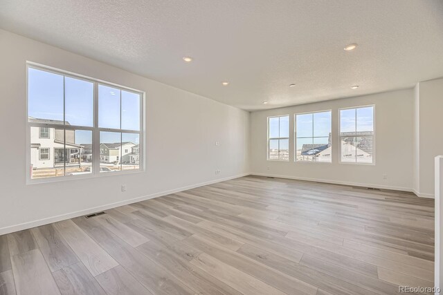 spare room with a textured ceiling and light wood-type flooring