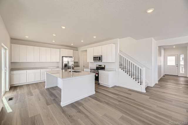 kitchen featuring white cabinetry, appliances with stainless steel finishes, sink, and a kitchen island with sink