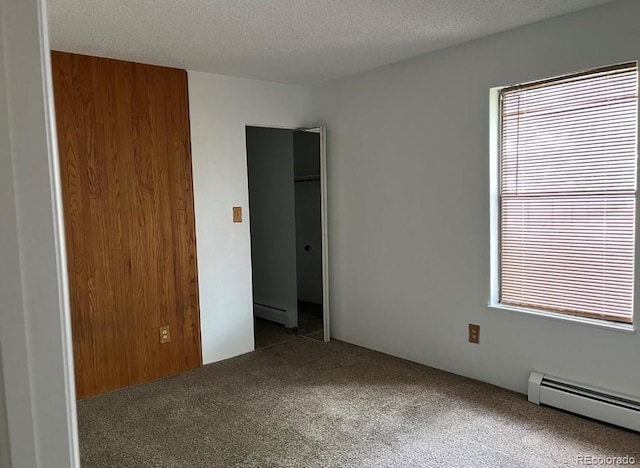 carpeted spare room featuring a closet, a textured ceiling, and a baseboard radiator