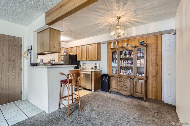 kitchen with a breakfast bar, a textured ceiling, stainless steel dishwasher, kitchen peninsula, and pendant lighting