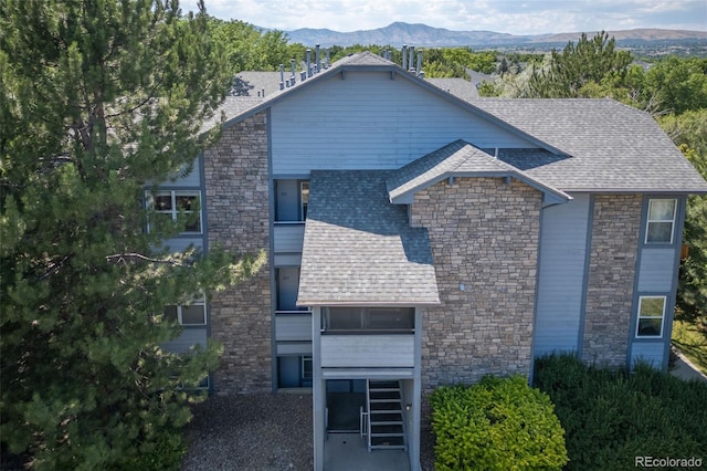 view of front of home with roof with shingles and a mountain view