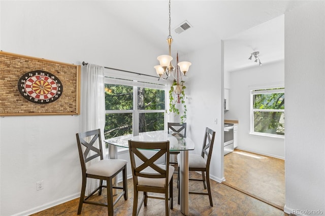 tiled dining room with lofted ceiling and an inviting chandelier