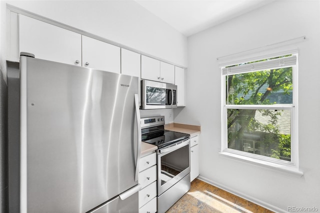 kitchen with light tile patterned flooring, appliances with stainless steel finishes, and white cabinetry