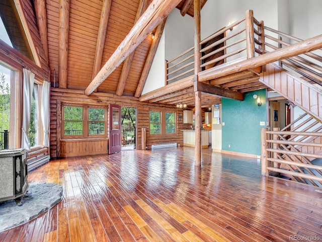 1000 Lodgepole Dr, Evergreen, CO 80439 - unfurnished living room featuring high vaulted ceiling, log walls, stairway, a wood stove, and a wooden ceiling with exposed beams