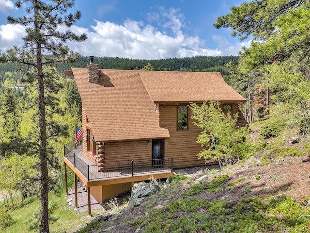 1000 Lodgepole Dr, Evergreen, CO 80439 - back of property featuring a forest view, log siding, a chimney, a shingled roof, and a deck