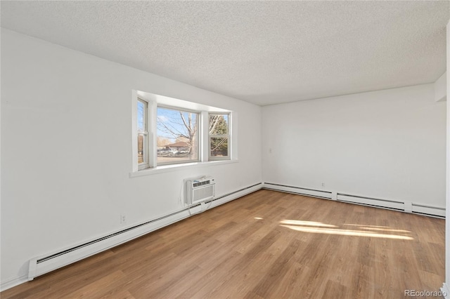 empty room with a baseboard heating unit, wood finished floors, and a textured ceiling