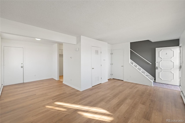 unfurnished living room with stairway, a textured ceiling, and light wood-style flooring