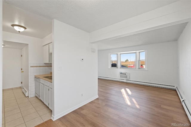 unfurnished room with light wood-style flooring, a textured ceiling, an AC wall unit, and a baseboard radiator