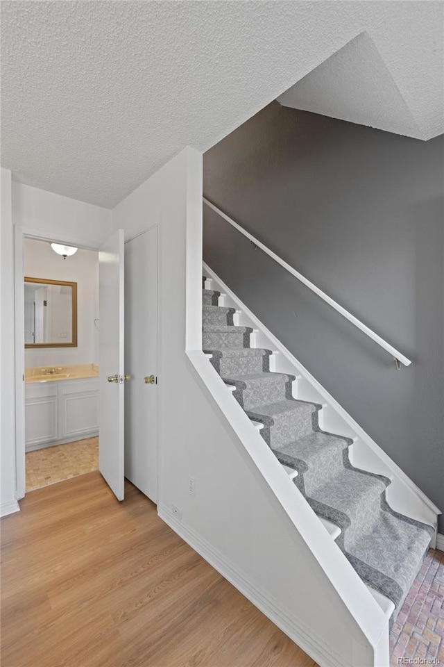 stairs featuring baseboards, a textured ceiling, and wood finished floors