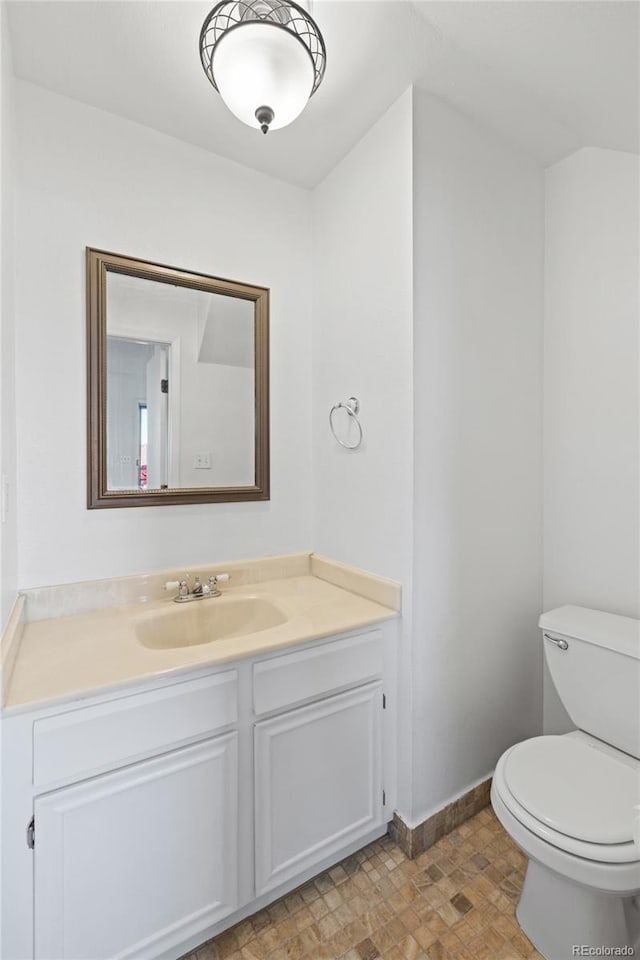 bathroom featuring baseboards, toilet, and vanity