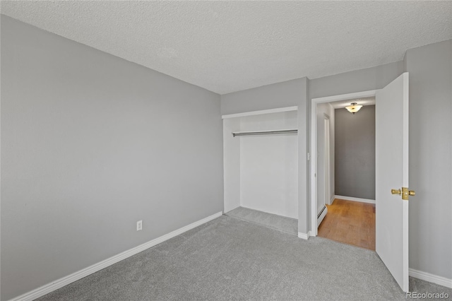 unfurnished bedroom with baseboards, a closet, a textured ceiling, carpet flooring, and baseboard heating