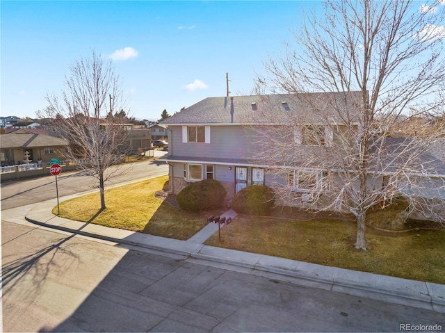 view of front of home featuring brick siding, roof with shingles, and a front lawn