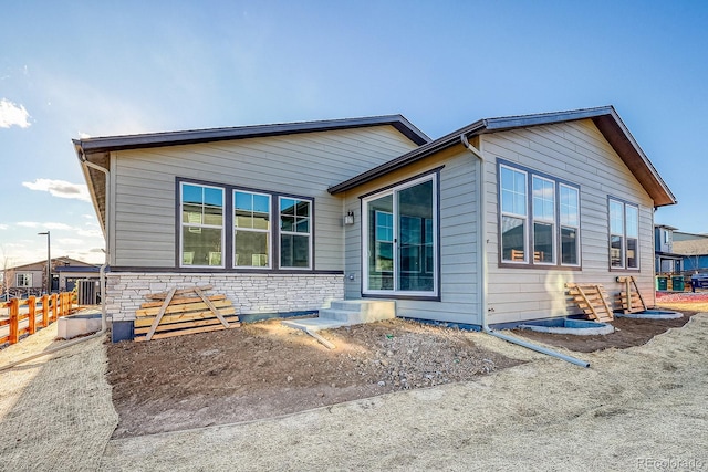 view of front of home featuring stone siding and fence