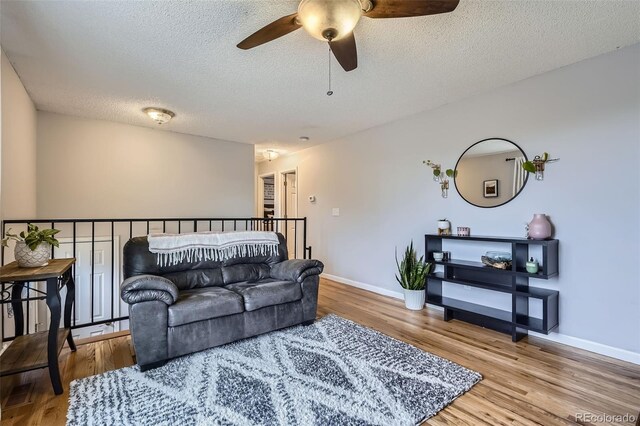 living room with baseboards, ceiling fan, a textured ceiling, and wood finished floors