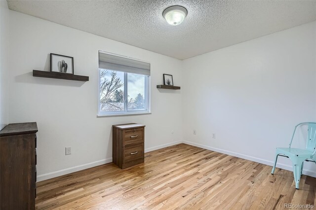 unfurnished bedroom with baseboards, a textured ceiling, and light wood-style flooring
