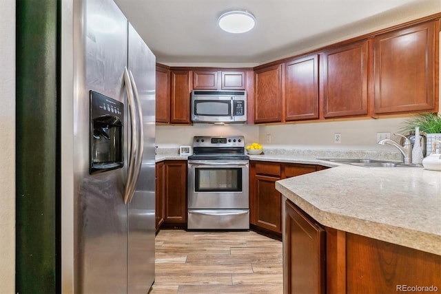 kitchen with appliances with stainless steel finishes, light hardwood / wood-style flooring, and sink