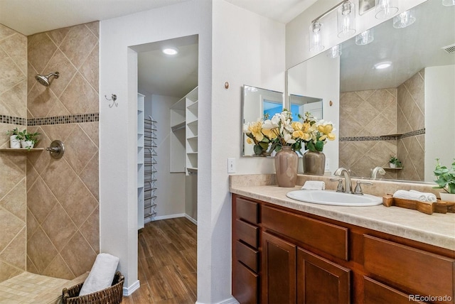 bathroom with a tile shower, hardwood / wood-style flooring, and vanity