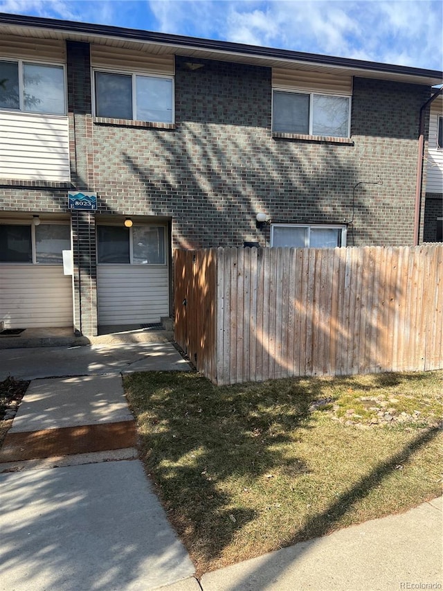 view of front of home with fence, a front lawn, and brick siding