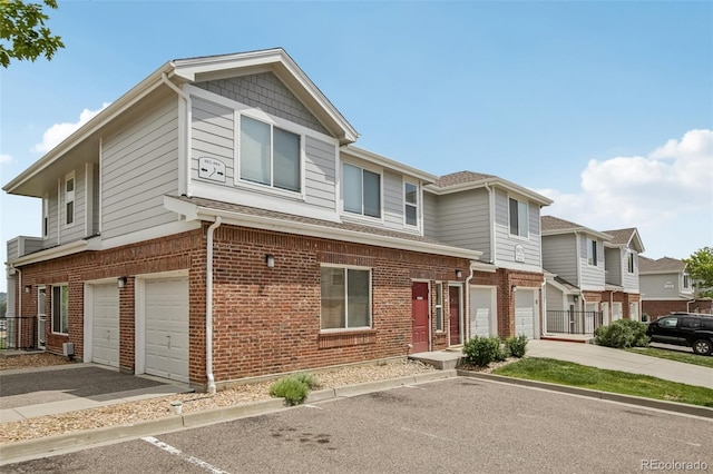 10129 W 55th Dr Unit 3, Arvada, CO 80002 - view of property featuring a garage, brick siding, driveway, and a shingled roof