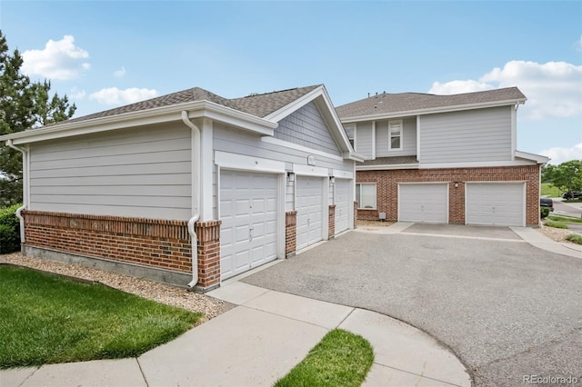 10129 W 55th Dr Unit 3, Arvada, CO 80002 - view of side of home featuring brick siding, asphalt driveway, a shingled roof, and a garage