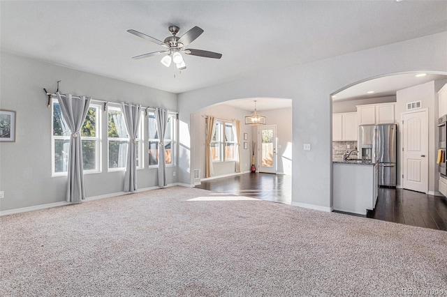 unfurnished living room with ceiling fan and dark carpet