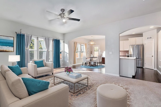 living room with dark hardwood / wood-style flooring and ceiling fan with notable chandelier