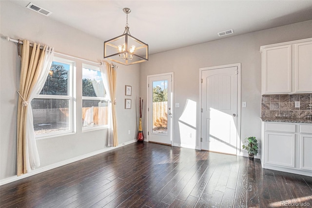 unfurnished dining area with an inviting chandelier and dark wood-type flooring