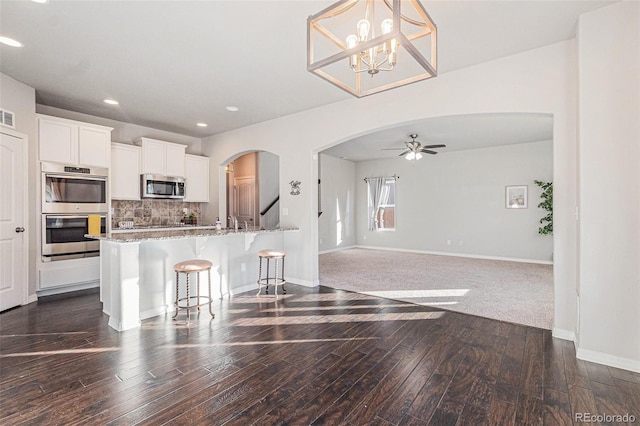 kitchen with pendant lighting, a breakfast bar, light stone counters, white cabinetry, and stainless steel appliances