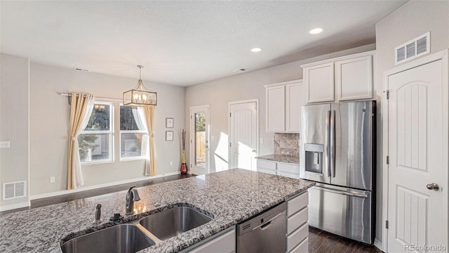 kitchen with sink, light stone counters, a notable chandelier, white cabinets, and appliances with stainless steel finishes