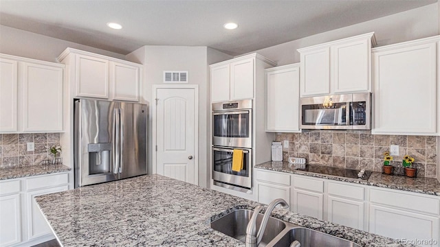 kitchen featuring decorative backsplash, light stone counters, stainless steel appliances, sink, and white cabinets