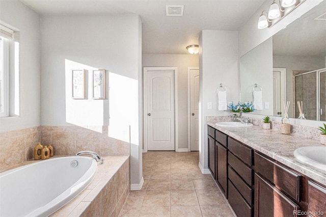 bathroom featuring plus walk in shower, vanity, and tile patterned floors