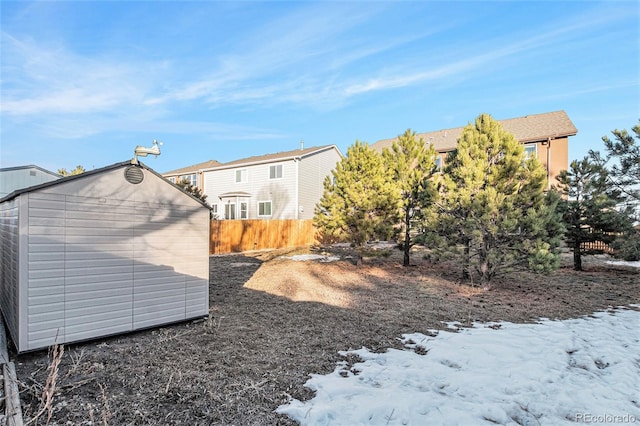 snowy yard featuring a storage shed