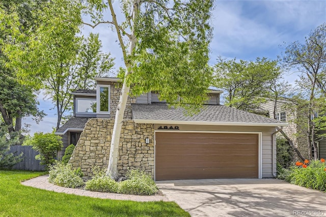 1540 W Briarwood Ave, Littleton, CO 80120 - view of front of house with concrete driveway, a garage, fence, stone siding, and roof with shingles
