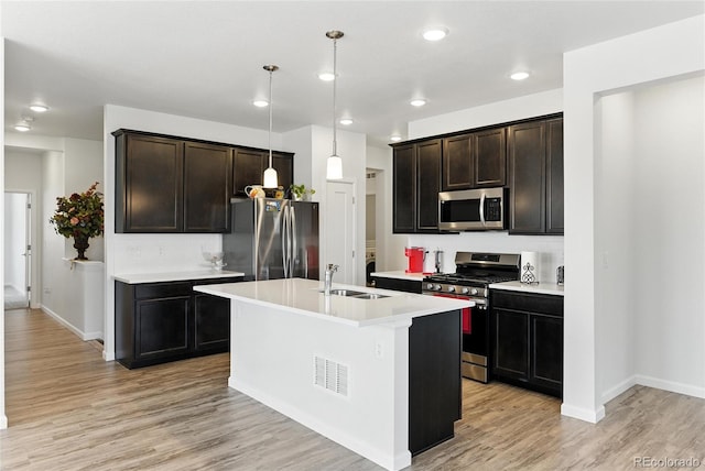 15501 E 112th Ave Unit 6F, Commerce City, CO 80022 - kitchen featuring appliances with stainless steel finishes, light countertops, light wood-style flooring, tasteful backsplash, and a center island with sink