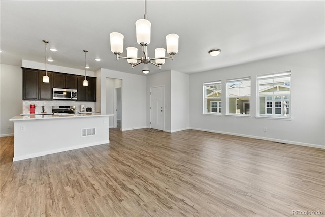 15501 E 112th Ave Unit 6F, Commerce City, CO 80022 - kitchen with stainless steel microwave, stove, light wood-style floors, light countertops, and recessed lighting