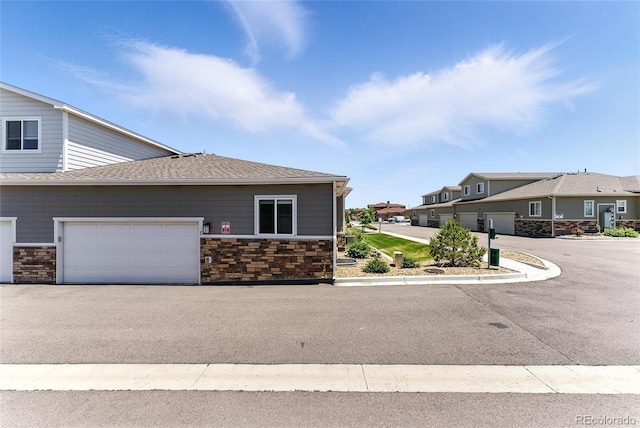 15501 E 112th Ave Unit 6F, Commerce City, CO 80022 - view of front facade with stone siding, a shingled roof, and a garage