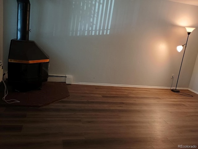 2565 S Sheridan Blvd Unit 20, Denver, CO 80227 - empty room featuring wood finished floors, a wood stove, baseboards, and a baseboard heating unit