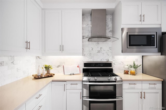 3301 Arapahoe Ave Unit 411, Boulder, CO 80303 - kitchen featuring appliances with stainless steel finishes, wall chimney exhaust hood, tasteful backsplash, white cabinetry, and light countertops